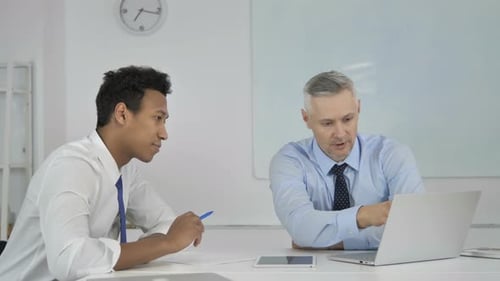 Two Men in Office Discussing Laptop Screen