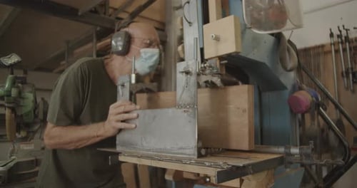 Woodworker Using Band Saw in Workshop