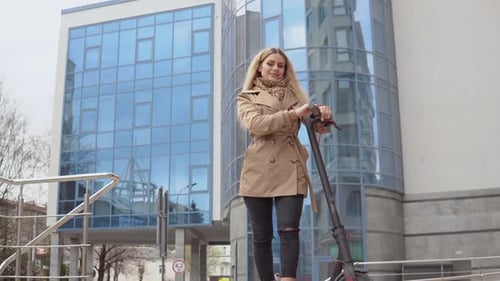 Woman with Scooter Stands in Front of Building