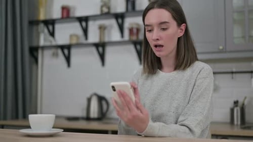 Concerned Woman Looking at Phone in Kitchen