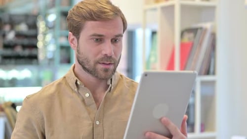 Man Cheers While Looking at Tablet Device