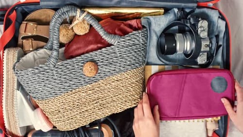 Top View of Female Hands Packing Suitcase