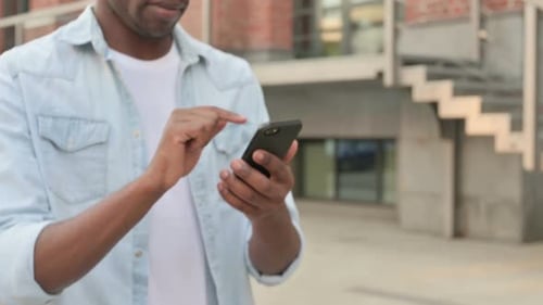 Close Up of Hands of African Man Using Smartphone While Walking in Street