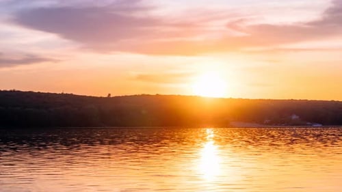 Light stretched clouds over evening sky, lake sunset skies time lapse shot. Sun disk ahead, hide beh