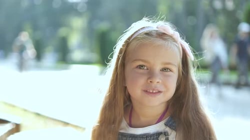 Portrait of Pretty Child Girl Standing in Summer Park Looking in Camera Smiling Happily