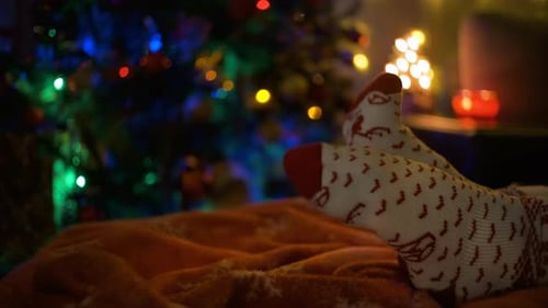 Festive Feet in Christmas Socks near Holiday Tree