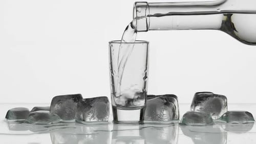 Shot Glass Being Filled With Clear Liquid and Ice