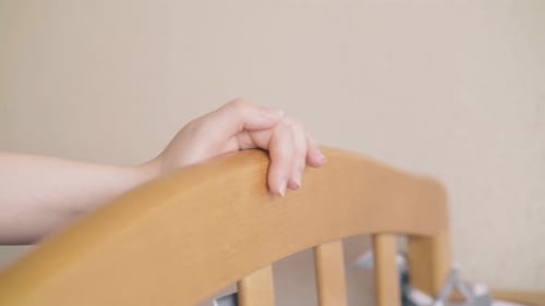 Woman's Hand Resting on a Baby Crib