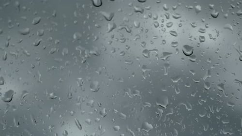 Rain Drops Slowly Collecting on Glass Window