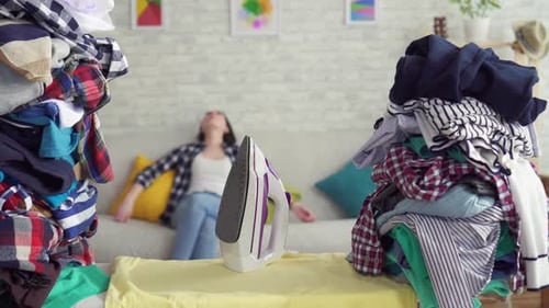 Overwhelmed Woman Surrounded by Laundry at Home