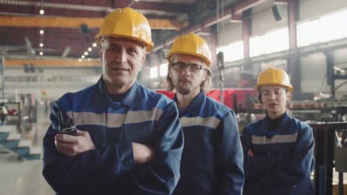 Smiling Plant Supervisor With Workers Posing For Camera