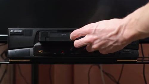 Hand Inserts VHS Tape Into a VCR