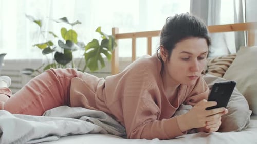 Woman Lies in Bed Using Mobile Phone