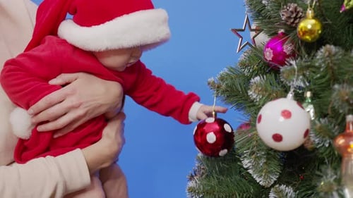 Infant Reaching for Christmas Ornament on a Tree