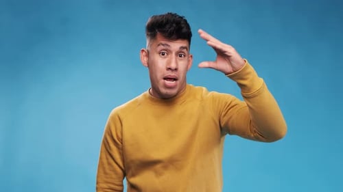 Junger Mann zeigt Bla-Bla-Gesten, während er vor einem isolierten Hintergrund steht. Zeitlupe.