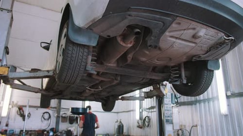 Auto Mechanic Repairs Car on the Lift in the Service Station