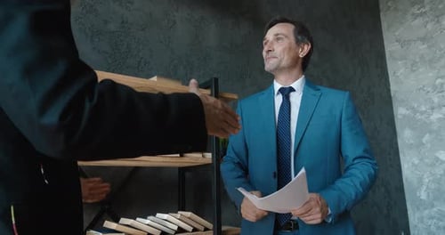 Two Mature Businessmen Shake Hands in a Modern Office