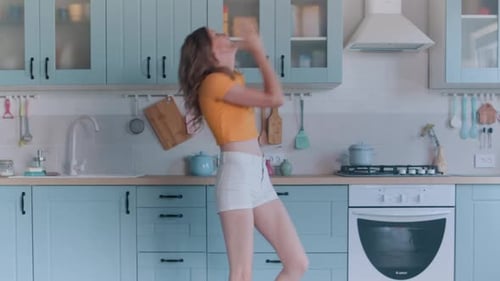 Woman Dancing Joyfully in a Pastel Blue Kitchen
