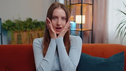 Surprised Woman Reacts to News on Couch