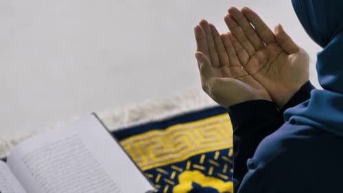 Eine junge muslimische Frau im Hijab betet, verherrliche Allah und praktiziert den islamischen Glauben in der Moschee.