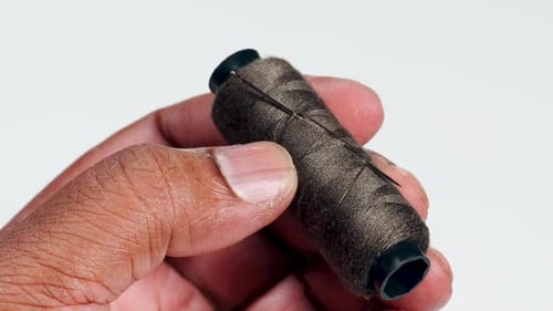 Fingers Hold Brown Thread And Needle