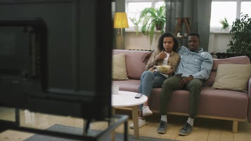 Couple Watching Scary Movie on Television at Home
