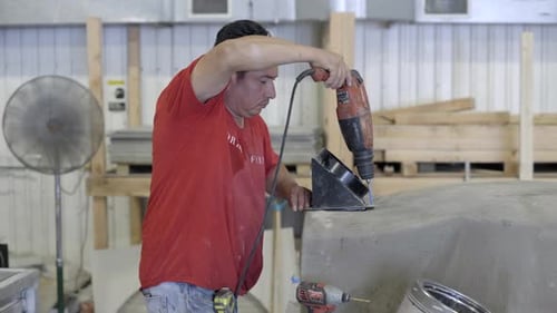 Worker drilling a hole into oven in workshop