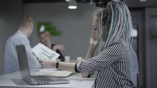 Side View Portrait of Concentrated Millennial Woman Working on Laptop in Office