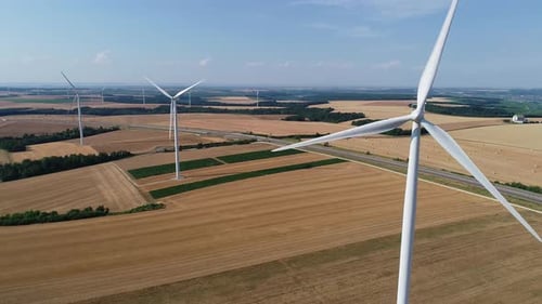 Large Wind Turbines with Blades in Field Aerial View Bright Orange Sunset Blue Sky Wind Park Slow