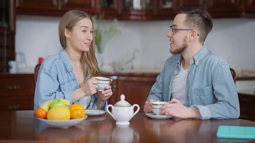 Couple Drinking Tea and Talking at Dining Table