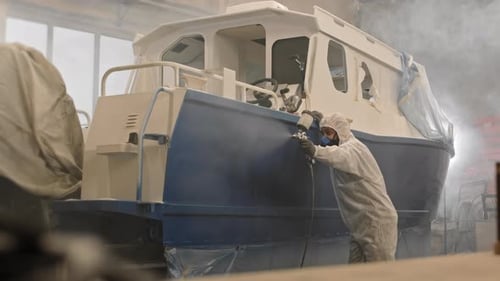 Man Spray Painting Boat in Industrial Workplace