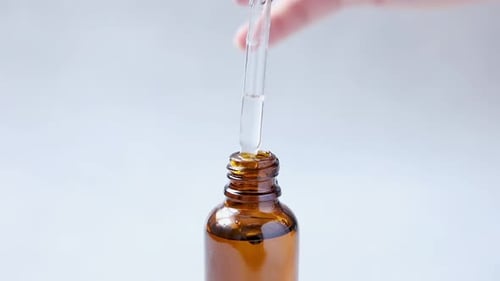 Dropper Dispersing Clear Liquid into Amber Bottle