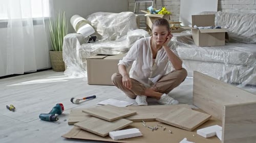 Tired Woman Looking at Disassembled Furniture