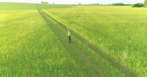 Sporty Child Standing in Green Wheat Field with Raised Hands Up
