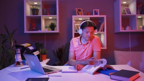 Young Adult Studying at Home with Laptop and Books