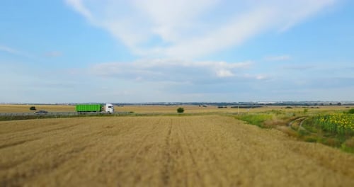 The Road Between The Wheat Field On Which Trucks Move