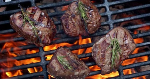 Close-up of steaks on a grilling with rosemary