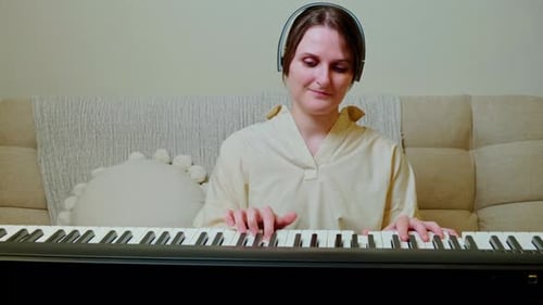 Young Woman Plays Piano with Headphones on Sofa