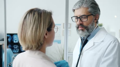 Experienced Cardiologist Examining Woman with Stethoscope in Hospital Office Room