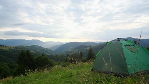 Touristenzelt steht auf grünem Gras vor einem Hintergrund von Bergen