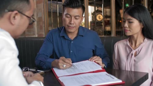 Couple Signing Paperwork at a Business Meeting