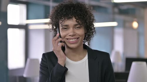 Woman Smiling and Talking on Phone in Office
