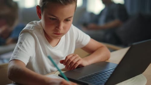 Kid Writing Homework at Home. Serious Boy Using Laptop for Distance Education