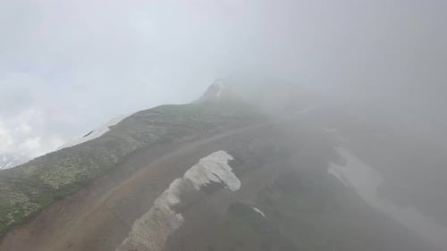 Stone Column Peak in Clouds Flying Over in Summer Day