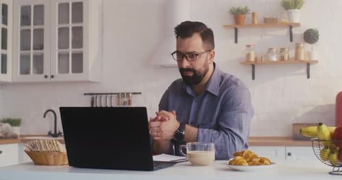 Bearded Man Working on Laptop During Video Call
