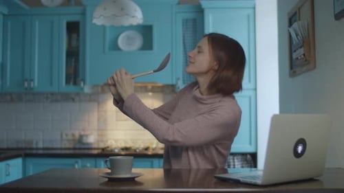 Woman Dancing and Singing with Spoon in Kitchen