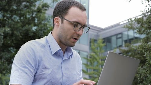 Man Types on Laptop in Urban Setting