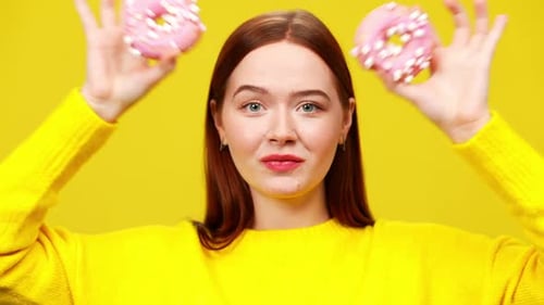 Young Woman Smiles with Donuts on Yellow Background