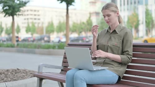 Woman With Headache Using Laptop on City Bench