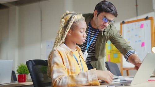 Woman Works on Laptop with Man Helping